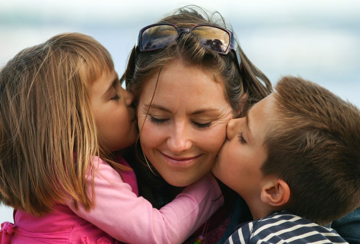 Two children hugging their mother